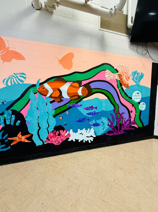 Colorful mural of underwater scene with fish and coral on a wall by New Jersey public artist Chanelle René located at Vineland High School.