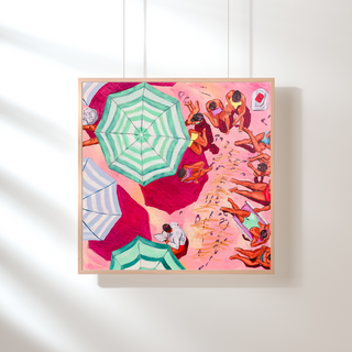 Framed artwork of a beach scene with people and umbrellas on a white wall.